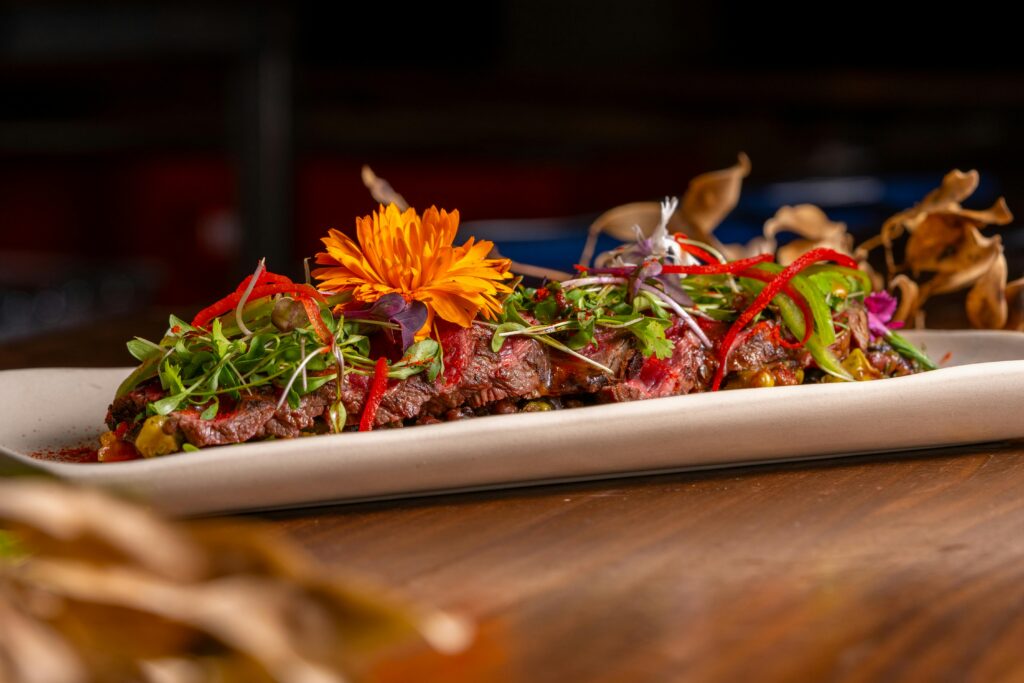 A Vibrant Gourmet Dish topped with microgreens and an edible flower, served on a sleek plate.