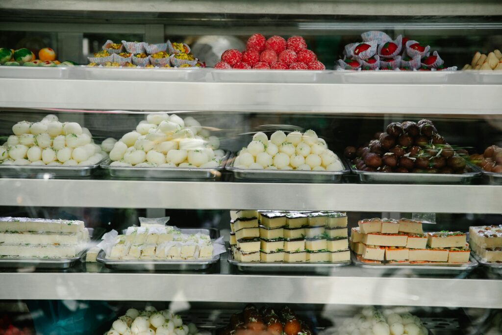A vibrant assortment of colorful pastries and sweets displayed on trays in a bakery.