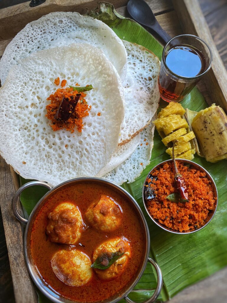 Appam And Egg Curry And Black Tea Served On a Banana Leaf